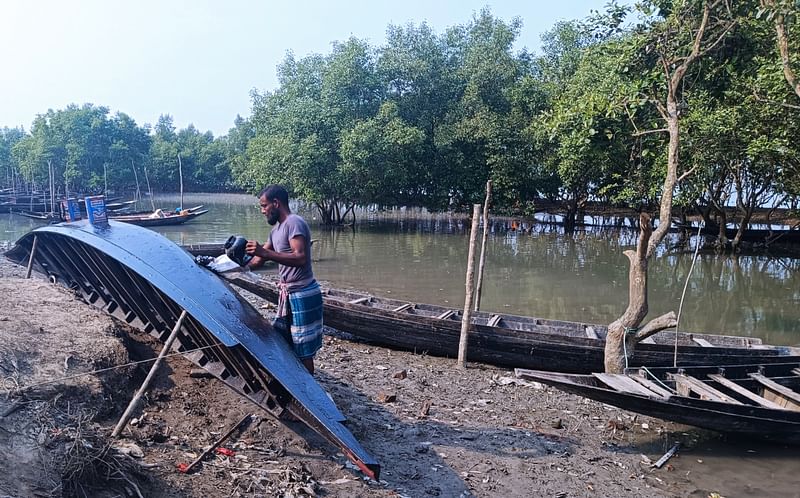 নৌকা টেকসই করতে আলকাতরা দিচ্ছেন এক জেলে। গত মঙ্গলবার সকালে কয়রা উপজেলার সুন্দরবন-সংলগ্ন জোড়শিং এলাকায়